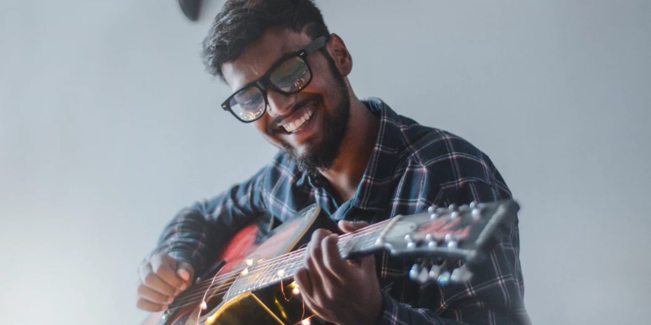 photo of guitar player wearing glasses and smiling